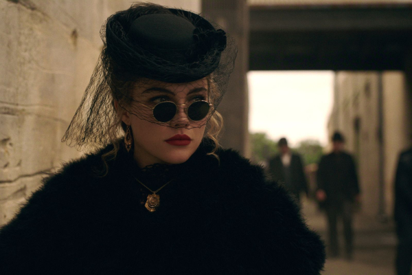 Florence Pugh as Cathy Ames in episode 106 of East of Eden  wearing a black hat black sunglasses red lipstick and a...